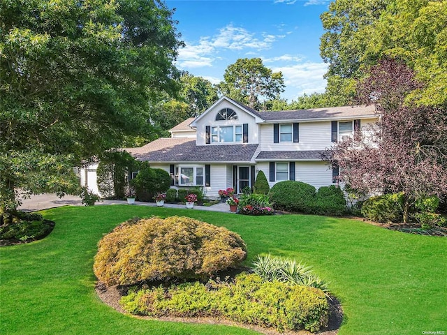 traditional home featuring a front yard and an attached garage