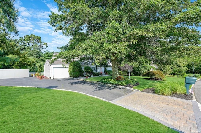 view of front of house featuring driveway, an attached garage, a front yard, and fence