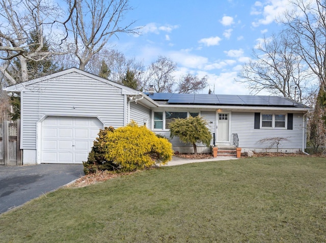 ranch-style home with a garage, driveway, solar panels, and a front yard