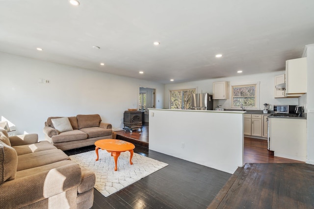 living room with recessed lighting, dark wood finished floors, and a wood stove