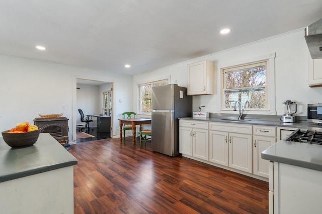 kitchen with a sink, stainless steel appliances, white cabinetry, wall chimney exhaust hood, and dark wood-style flooring