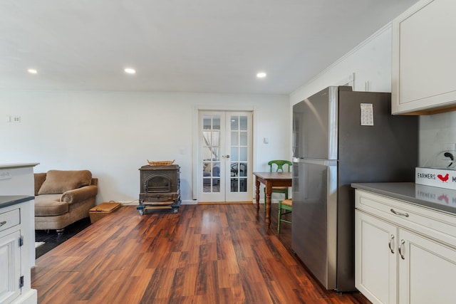 kitchen with dark countertops, dark wood finished floors, freestanding refrigerator, french doors, and a wood stove