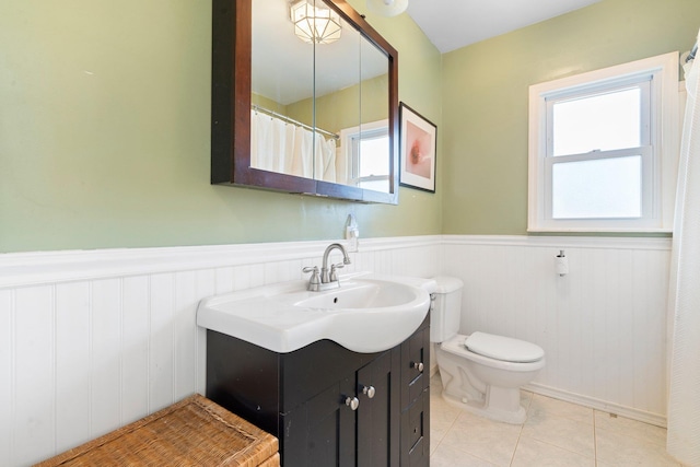 bathroom featuring vanity, tile patterned floors, a wainscoted wall, and a wealth of natural light