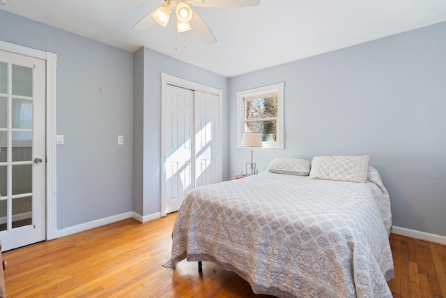 bedroom with a closet, a ceiling fan, light wood-type flooring, and baseboards