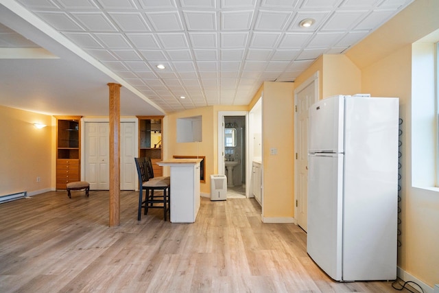 kitchen with a kitchen bar, freestanding refrigerator, recessed lighting, light wood-style floors, and baseboards