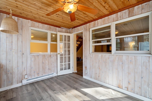 spare room with wood walls, wood ceiling, and a baseboard heating unit