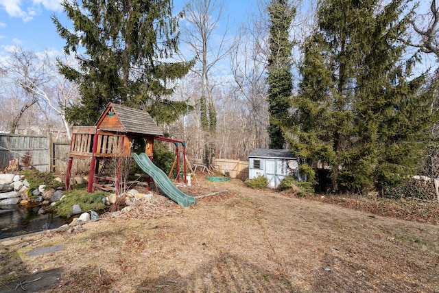 view of play area featuring an outbuilding, a shed, and fence