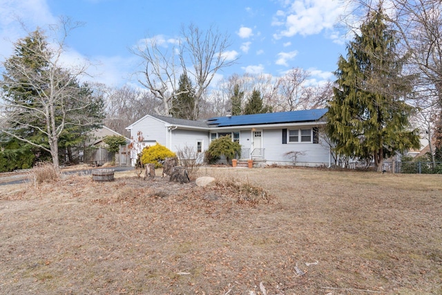 ranch-style home with fence and roof mounted solar panels