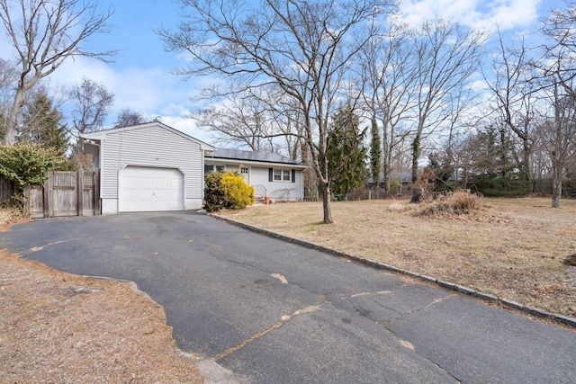 single story home with an attached garage, roof mounted solar panels, fence, and driveway