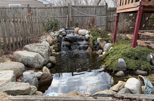 view of yard with a small pond and fence