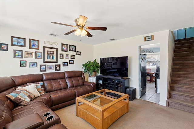 living area with light colored carpet, stairway, a ceiling fan, and visible vents