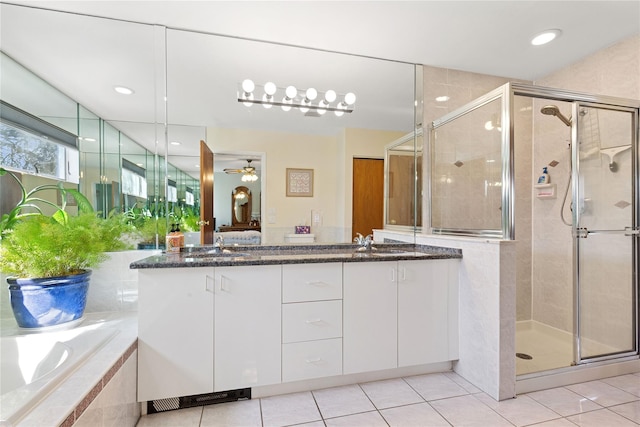 bathroom featuring tile patterned flooring, a stall shower, a bath, and double vanity