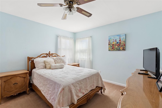 bedroom with a ceiling fan, baseboards, and light carpet