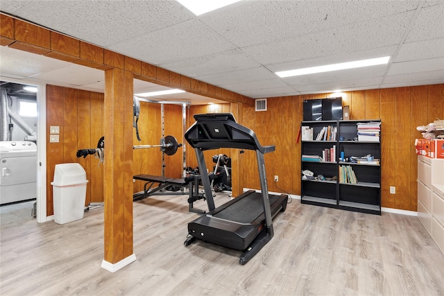 workout room with visible vents, wooden walls, washer / dryer, wood finished floors, and a paneled ceiling