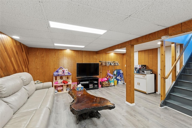 living room with wooden walls, stairs, and light wood-style floors