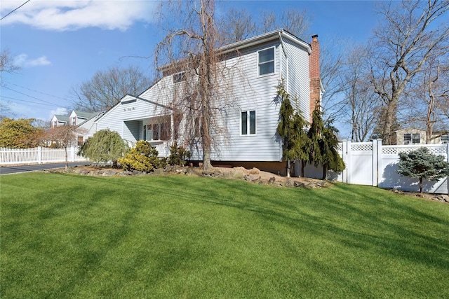 exterior space with a chimney, a yard, and fence