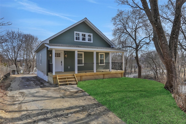 view of front of home featuring aphalt driveway, roof with shingles, a porch, and a front lawn