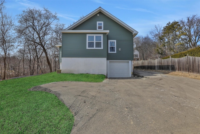 view of side of home with a lawn, driveway, an attached garage, and fence