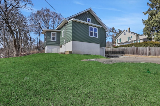 view of home's exterior with a yard, driveway, an attached garage, and fence