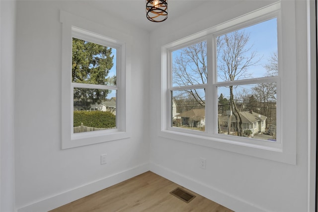 spare room with baseboards, visible vents, and light wood finished floors