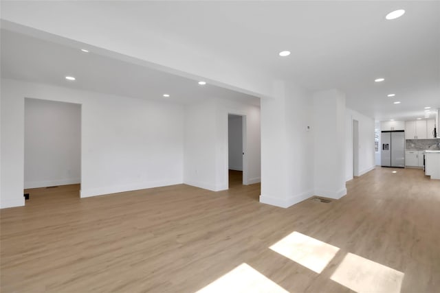 unfurnished living room featuring recessed lighting, baseboards, and light wood finished floors