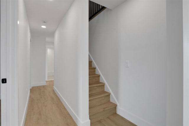 corridor featuring stairs, baseboards, and light wood-type flooring