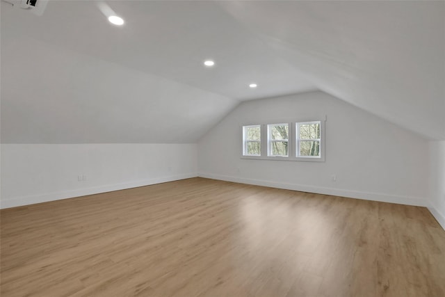 additional living space with light wood-type flooring, lofted ceiling, and baseboards