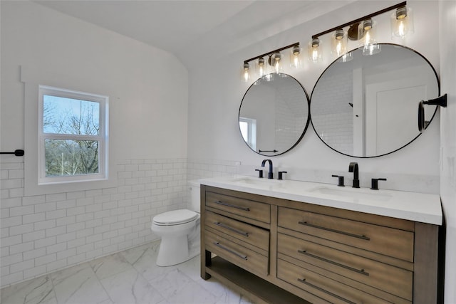 full bath with a sink, toilet, marble finish floor, and double vanity