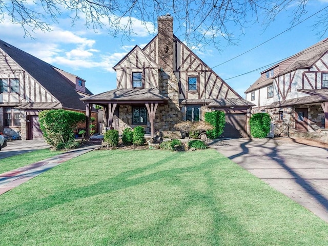 tudor house with a front yard, a chimney, concrete driveway, a garage, and stone siding