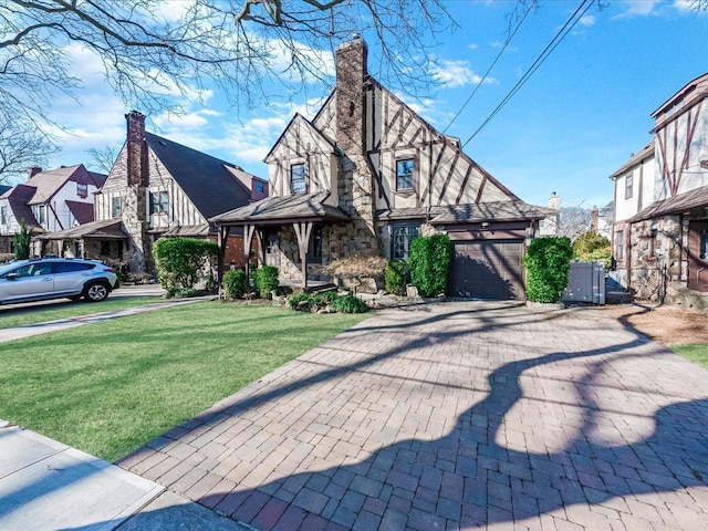 view of front of property featuring a garage, decorative driveway, a chimney, and a front lawn