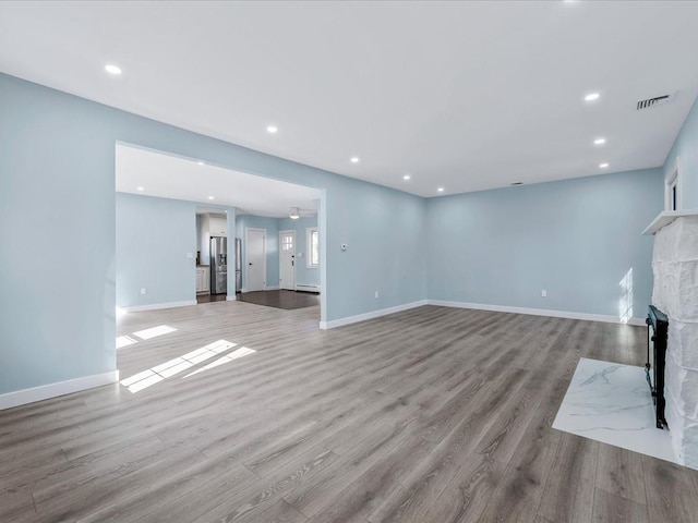 unfurnished living room featuring visible vents, recessed lighting, light wood-style floors, and a fireplace with flush hearth