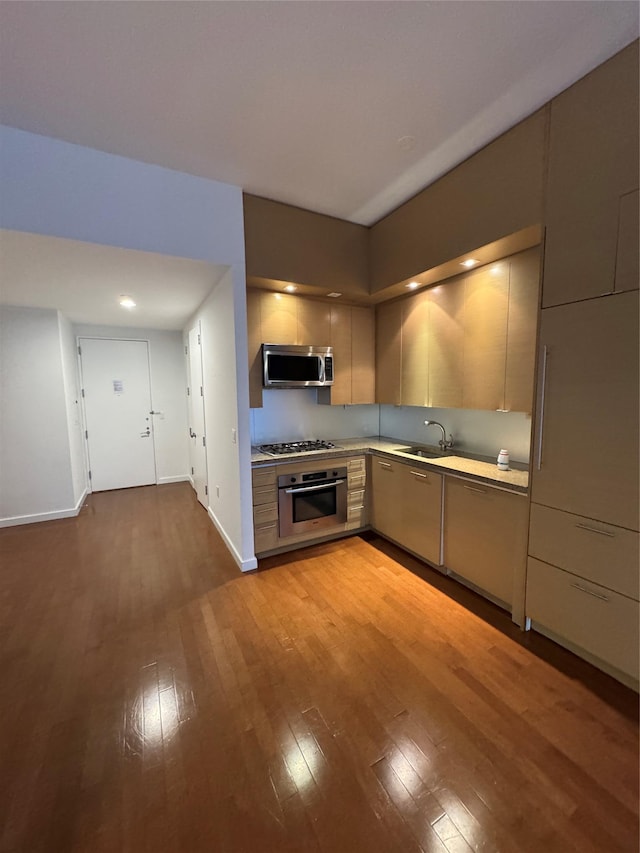 kitchen with a sink, light countertops, hardwood / wood-style flooring, appliances with stainless steel finishes, and modern cabinets