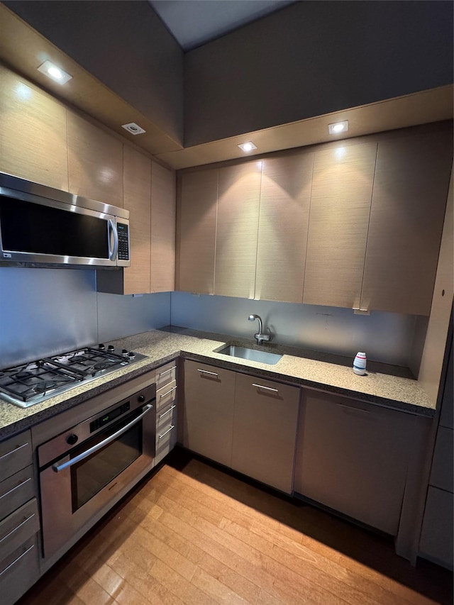 kitchen with a sink, stainless steel appliances, gray cabinetry, and modern cabinets