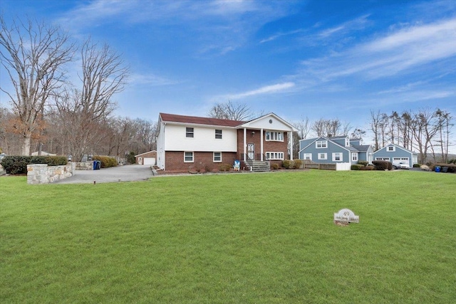 bi-level home featuring a front lawn, brick siding, a garage, and driveway