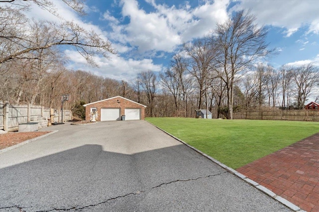 view of yard featuring a detached garage, an outdoor structure, and fence