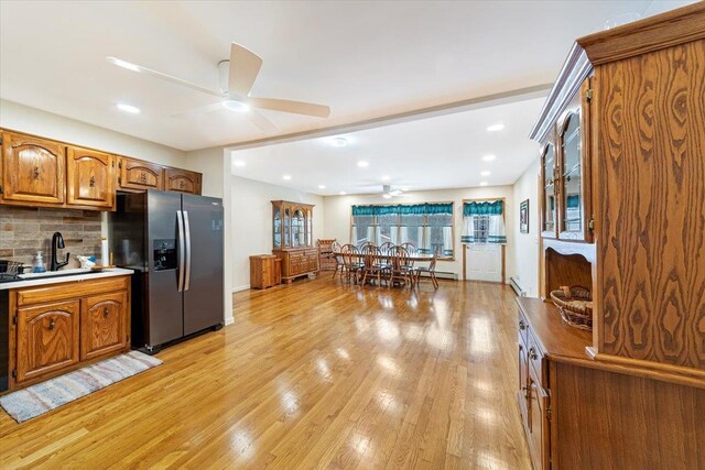 kitchen with a sink, light wood-type flooring, stainless steel fridge, and tasteful backsplash