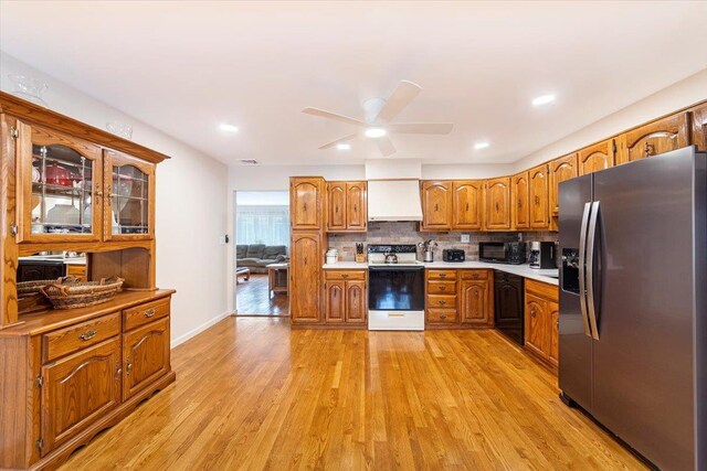 kitchen with brown cabinetry, stainless steel fridge with ice dispenser, light countertops, electric stove, and light wood-type flooring