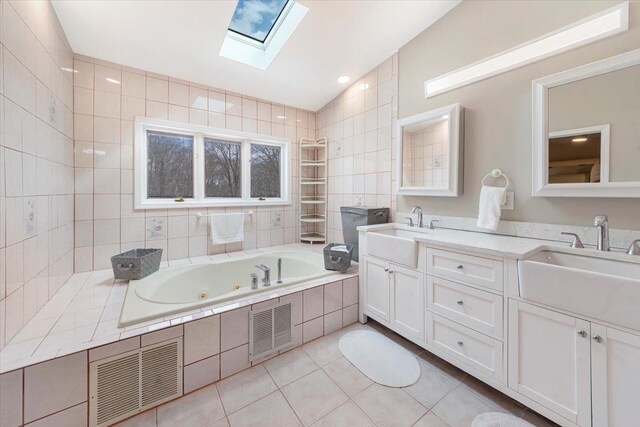 bathroom featuring visible vents, vaulted ceiling with skylight, and a sink