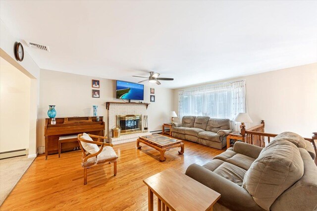 living area featuring visible vents, a ceiling fan, light wood-style floors, baseboard heating, and a brick fireplace