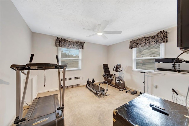 exercise room featuring radiator, baseboards, ceiling fan, a textured ceiling, and carpet flooring