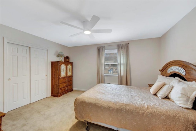 bedroom with a closet, baseboards, light colored carpet, and ceiling fan