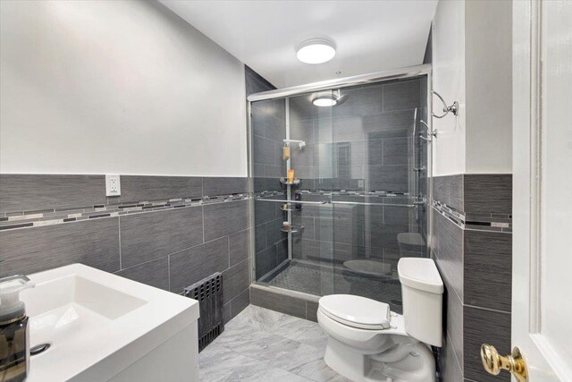 bathroom featuring a stall shower, toilet, tile walls, and vanity