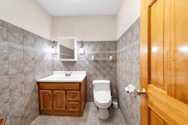 bathroom with tile patterned floors, toilet, tile walls, and vanity