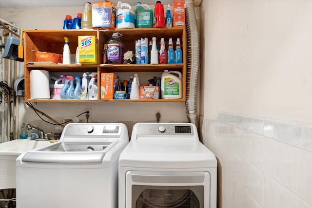 laundry area featuring a sink, laundry area, tile walls, and washer and clothes dryer