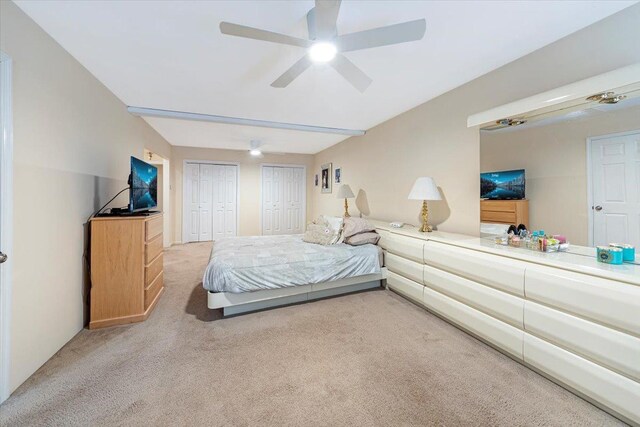 carpeted bedroom featuring a ceiling fan and multiple closets