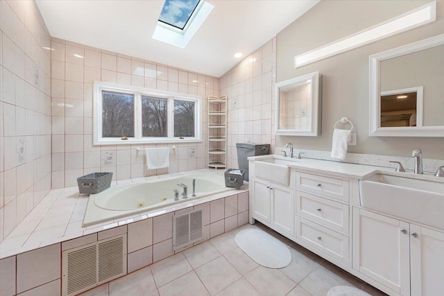 bathroom with visible vents, vaulted ceiling with skylight, and a sink