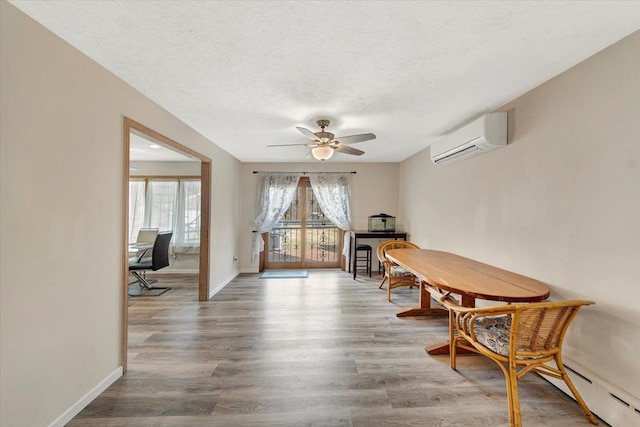 dining area featuring a wall mounted air conditioner, a baseboard heating unit, ceiling fan, and wood finished floors