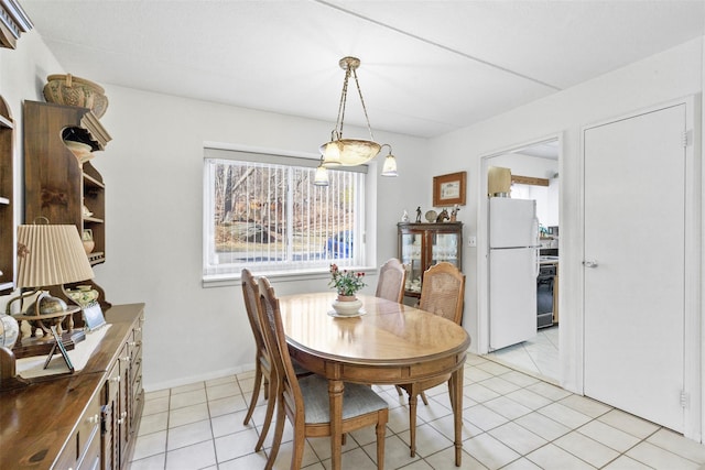 dining space featuring light tile patterned flooring and baseboards