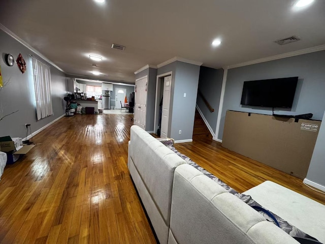 living area with visible vents, wood-type flooring, and ornamental molding