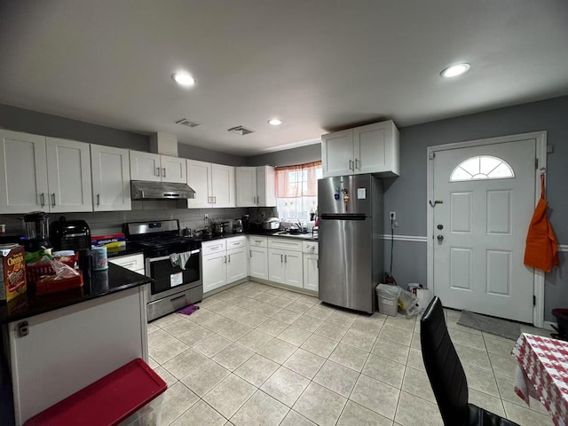 kitchen with dark countertops, visible vents, under cabinet range hood, appliances with stainless steel finishes, and a sink